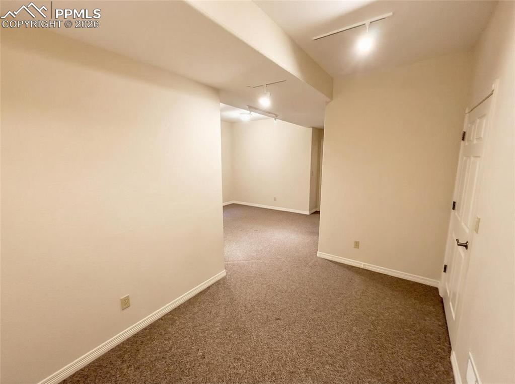 Image 26 of 30: Empty room featuring rail lighting and dark colored carpet
