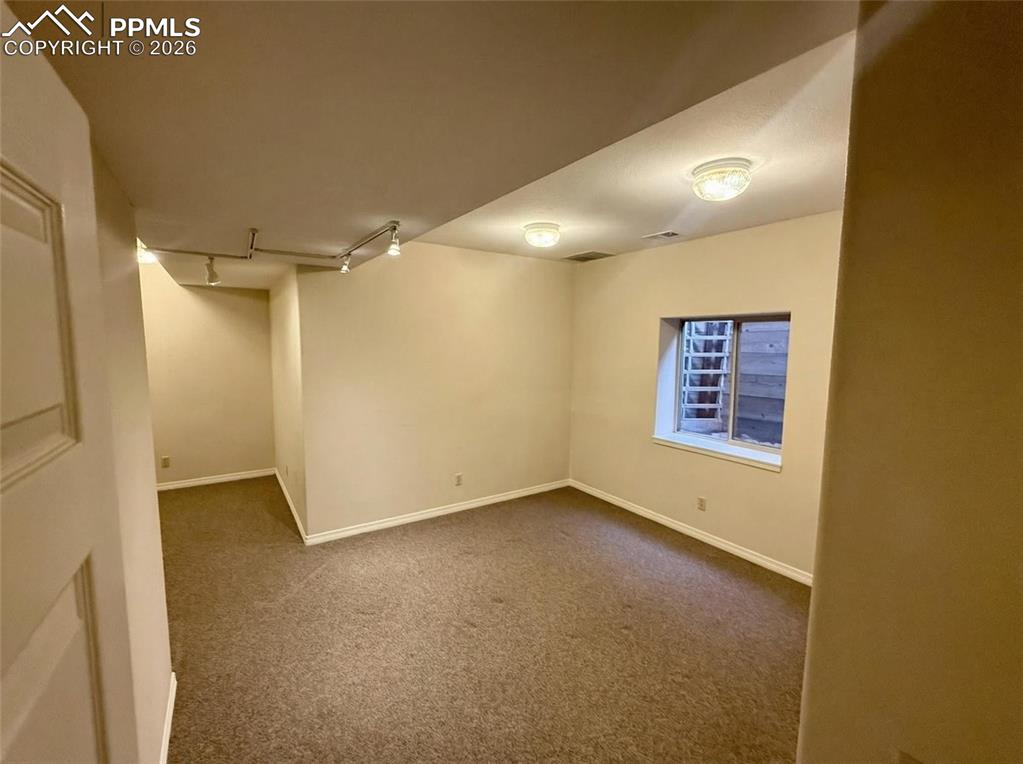 Image 27 of 30: Below grade area with dark colored carpet and rail lighting
