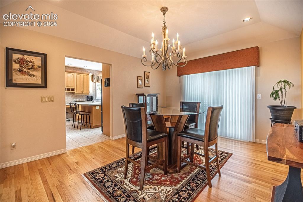 Image 27 of 50: Dining area featuring wood-finish flooring, a contemporary chandelier, and