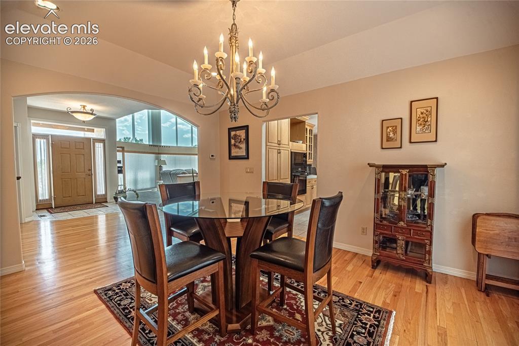 Image 28 of 50: Formal dining area featuring hardwood flooring, an overhead chandelier, and