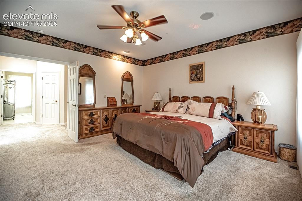 Image 30 of 50: Carpeted bedroom featuring a ceiling fan, recessed ceiling speaker, and a d