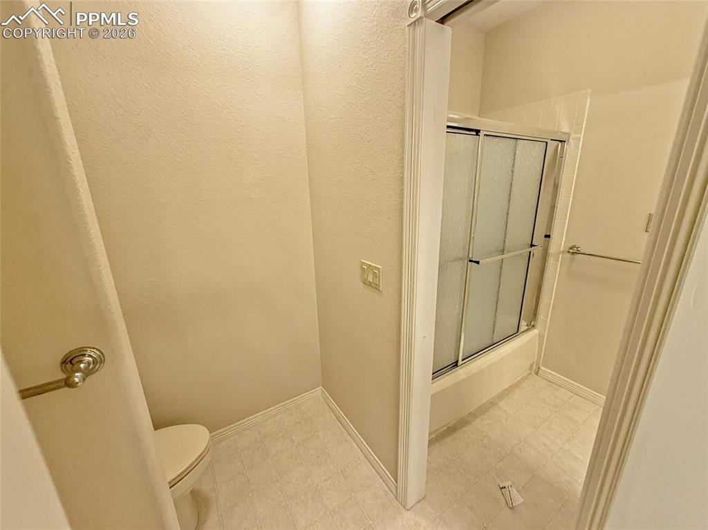 Image 32 of 38: Bathroom featuring light flooring, bath / shower combo with glass door, and