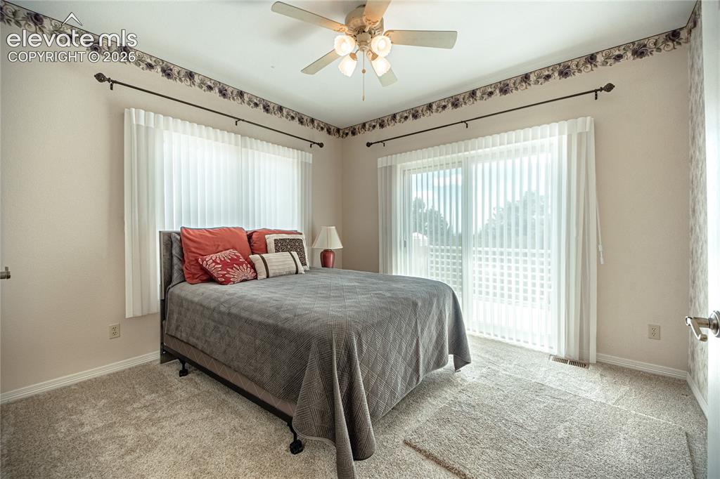Image 33 of 50: Carpeted room featuring a ceiling fan with light kit, a large window with v