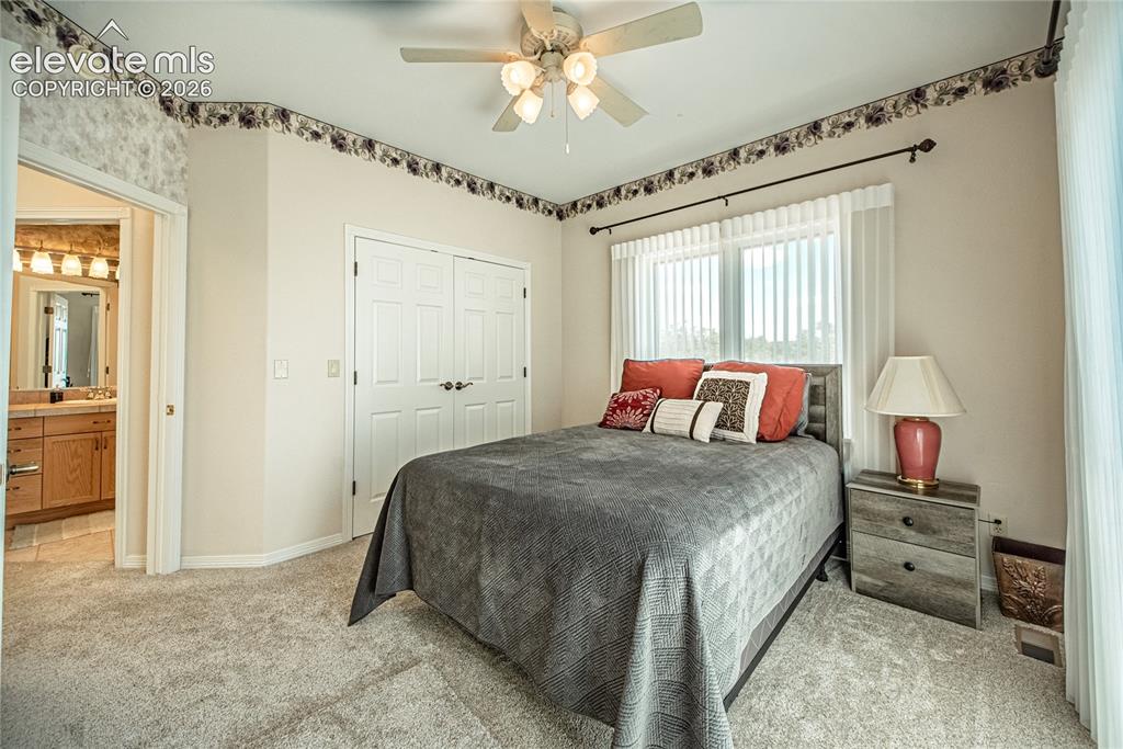 Image 34 of 50: Carpeted room featuring a ceiling fan, window with vertical blinds, bi-fold