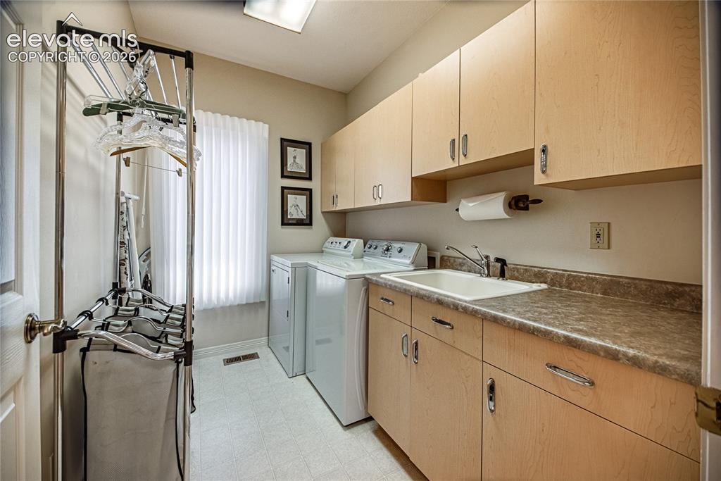 Image 36 of 50: Utility room featuring light wood-finish cabinetry, a utility sink with a c