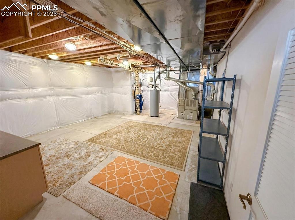 Image 38 of 38: Unfinished below grade area with water heater and heating unit