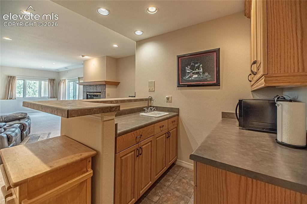 Image 39 of 50: Wet bar featuring wood cabinetry, a built-in sink, and a multi-level counte