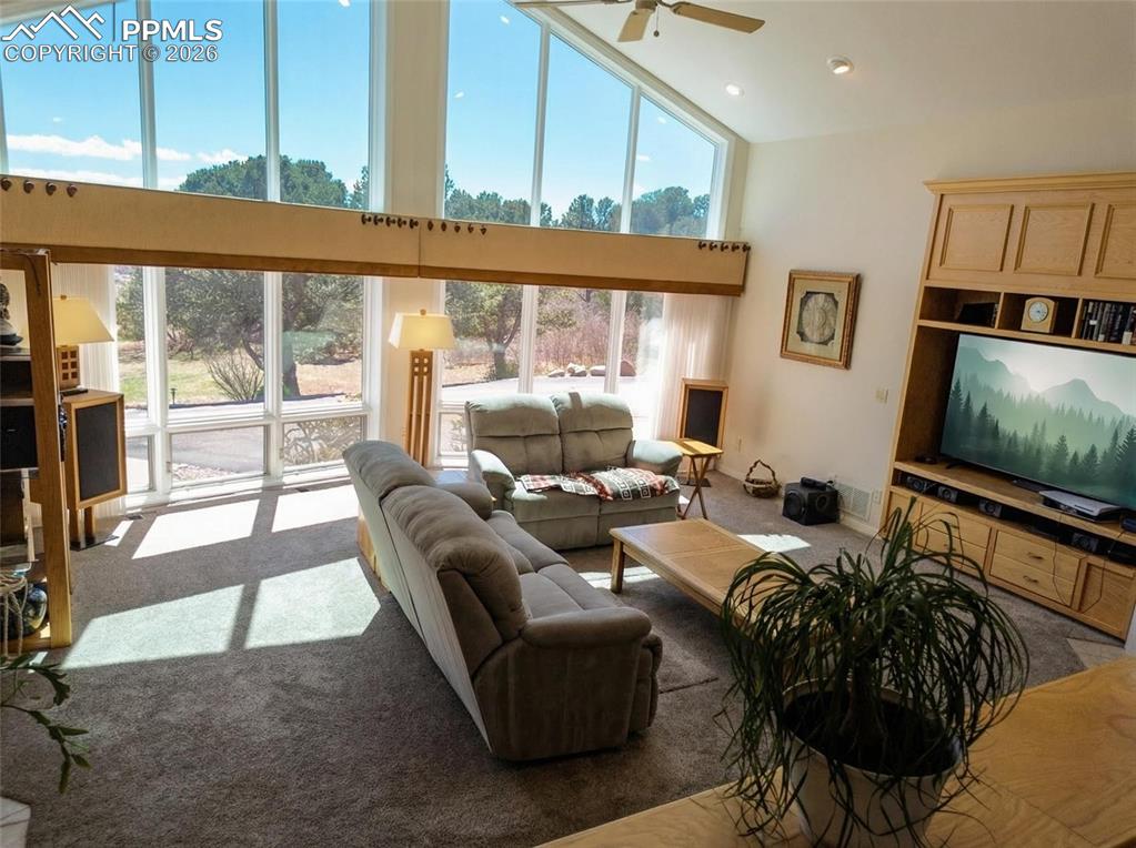 Image 4 of 30: Living area with carpet flooring, ceiling fan, lofted ceiling, and recessed