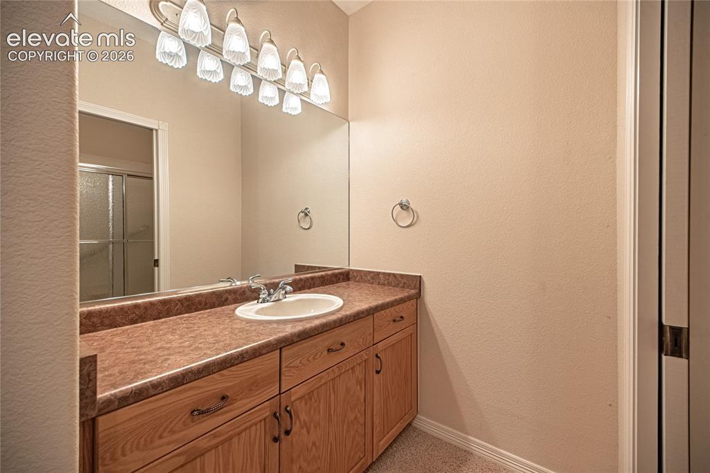Image 47 of 50: Bathroom vanity featuring a wood-finish cabinet with double doors and drawe