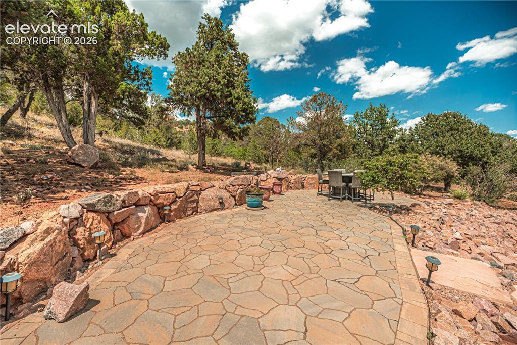 Image 9 of 50: Expansive flagstone patio area featuring a natural stone retaining wall, in
