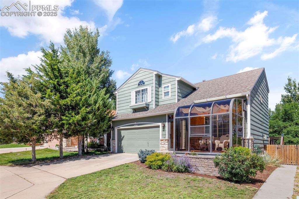 Caption: View of front facade featuring driveway, a shingled roof, an attached garage, and stone siding