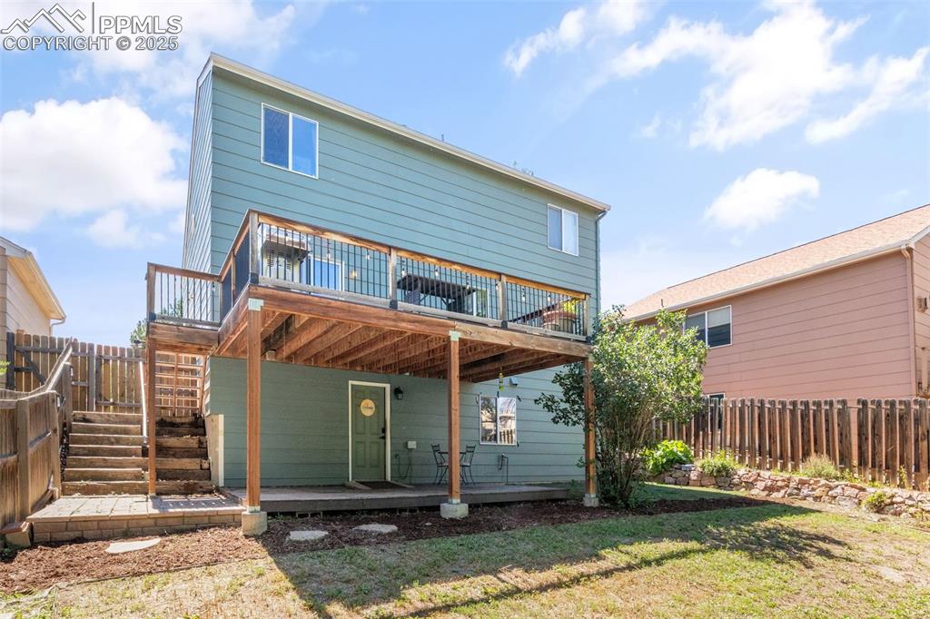 Image 33 of 46: Rear view of house featuring a fenced backyard, a wooden deck, and stairway
