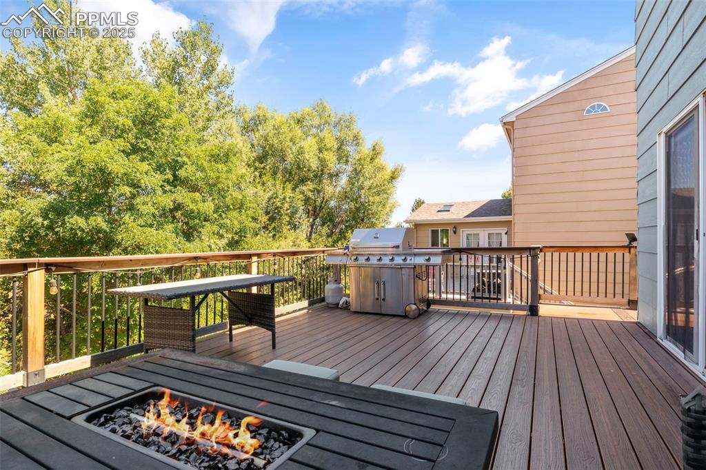 Image 8 of 46: Wooden deck with an outdoor fire pit and area for grilling