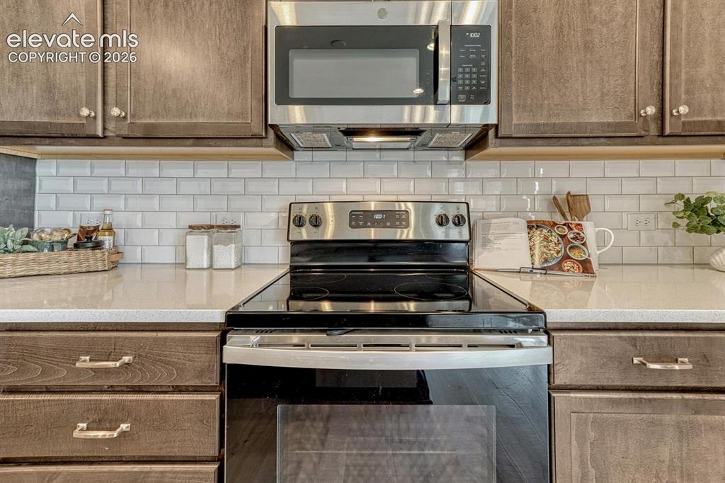 Image 19 of 50: The Island Kitchen features wood cabinetry and solid countertops with subwa