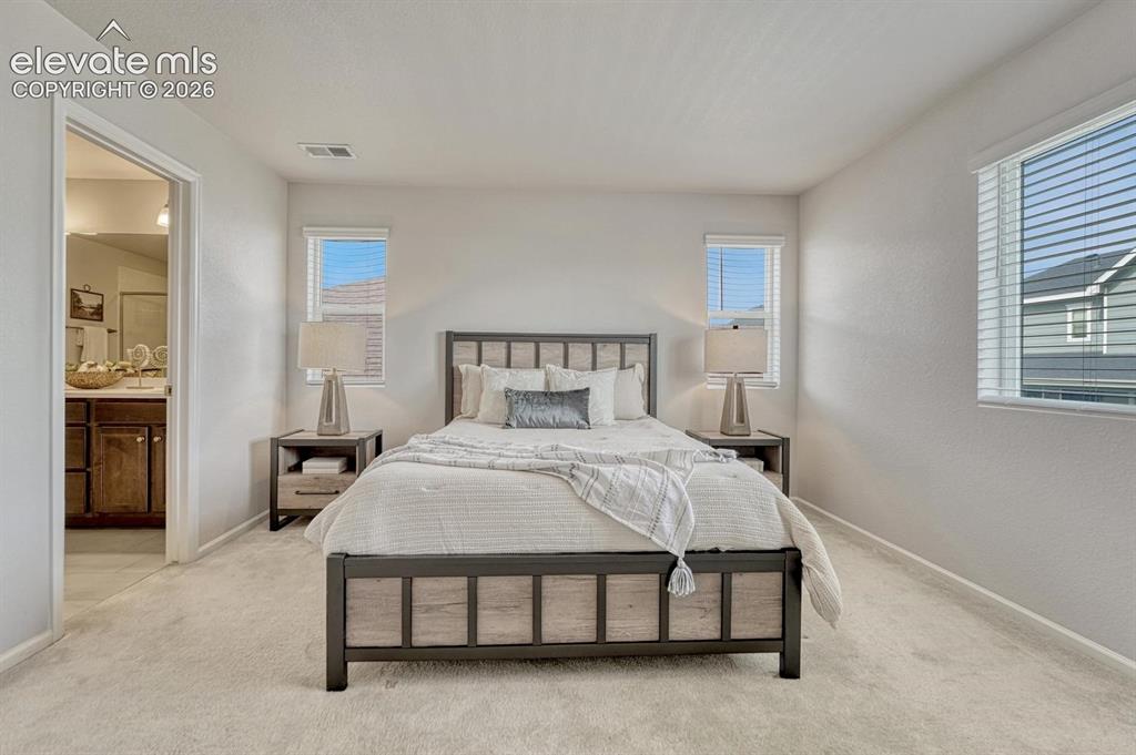 Image 30 of 50: The upper level Primary Suite is a private retreat with neutral carpet, an
