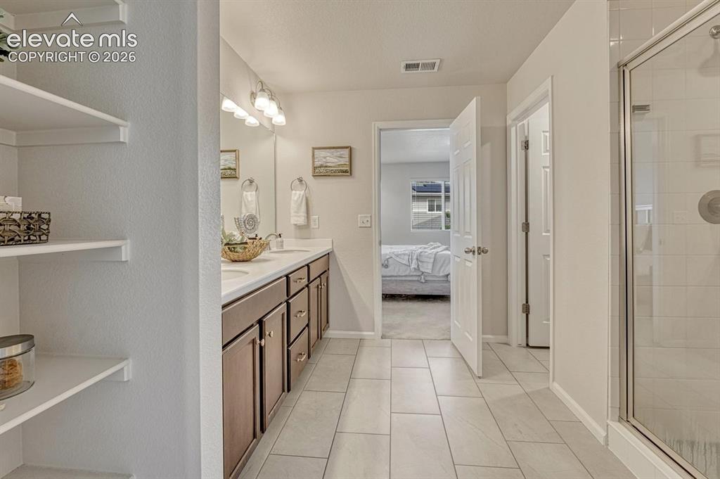 Image 35 of 50: Upper Level Primary Bathroom with tile floor, dual sink vanity, mirror, and