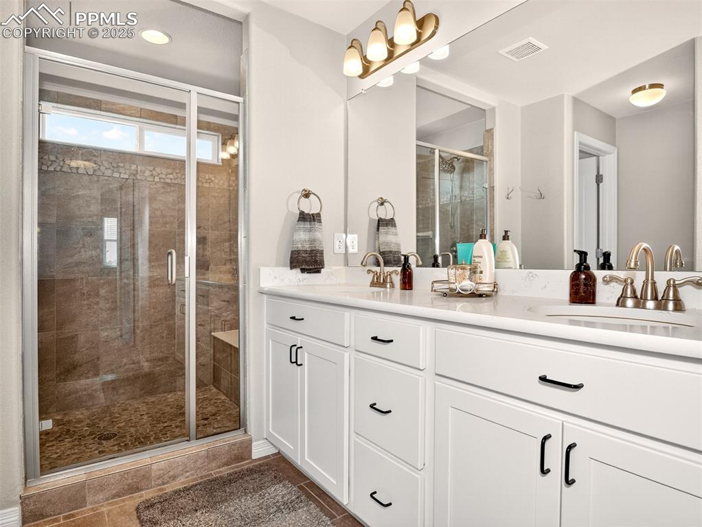 Image 21 of 48: Primary bath with double sinks, large shower with seat and dual shower head