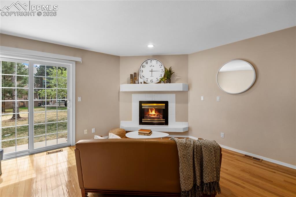 Image 9 of 37: The living room features real wood floors, a gas fireplace, and walks out t