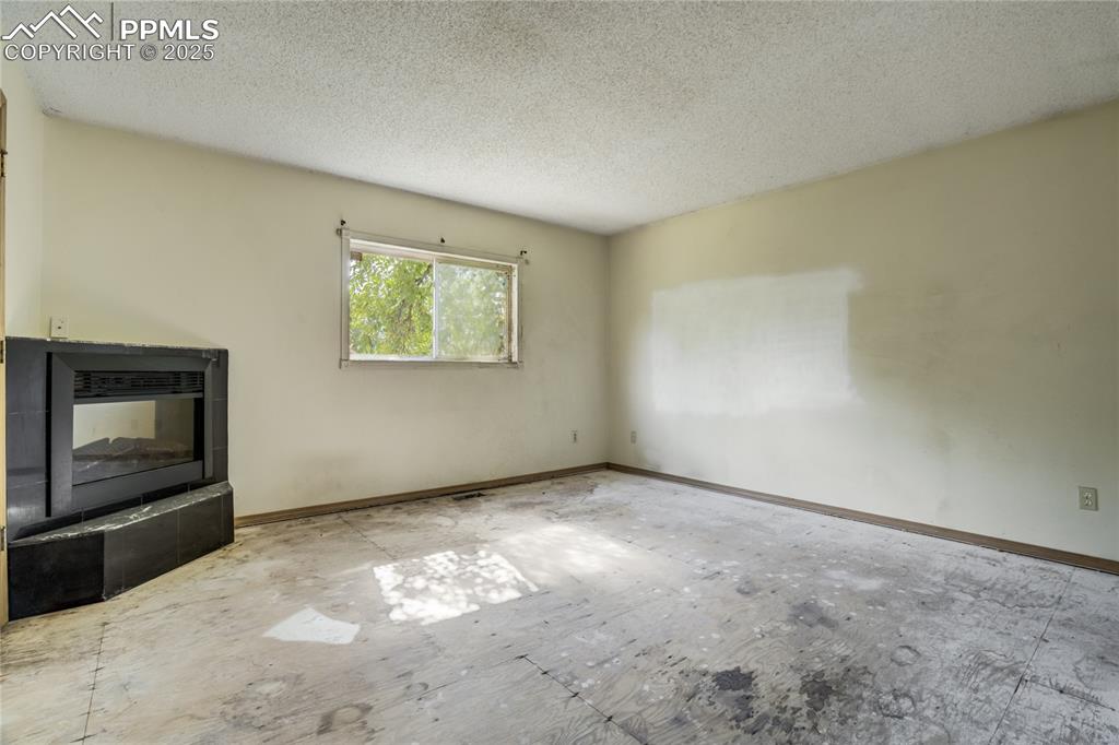 Image 10 of 24: Unfurnished living room with a textured ceiling and baseboards