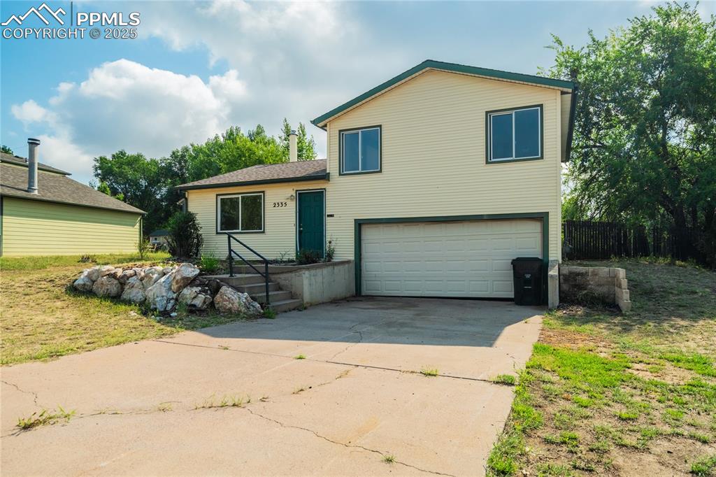 Image 2 of 24: Split level home featuring a garage and concrete driveway
