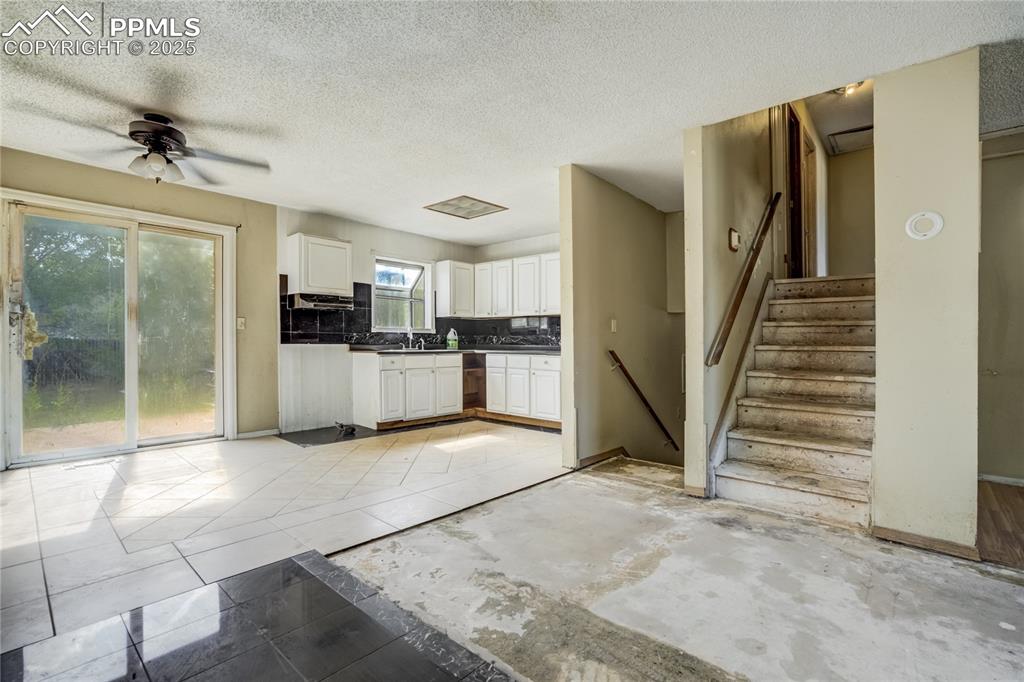 Image 5 of 24: Kitchen featuring a textured ceiling, white cabinets, a ceiling fan, dark c