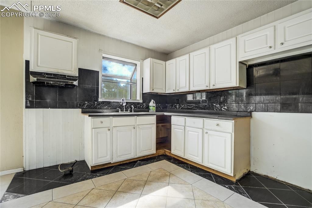 Image 6 of 24: Kitchen with tile patterned flooring, a textured ceiling, white cabinets, d