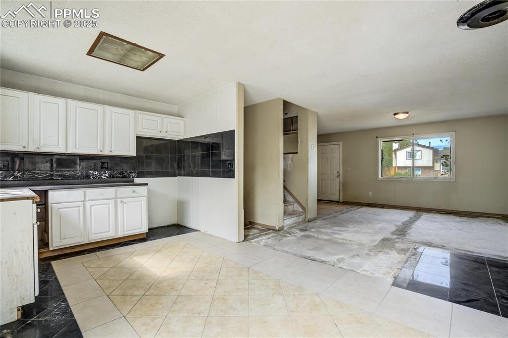 Image 8 of 24: Kitchen with white cabinets, open floor plan, and light tile patterned floo