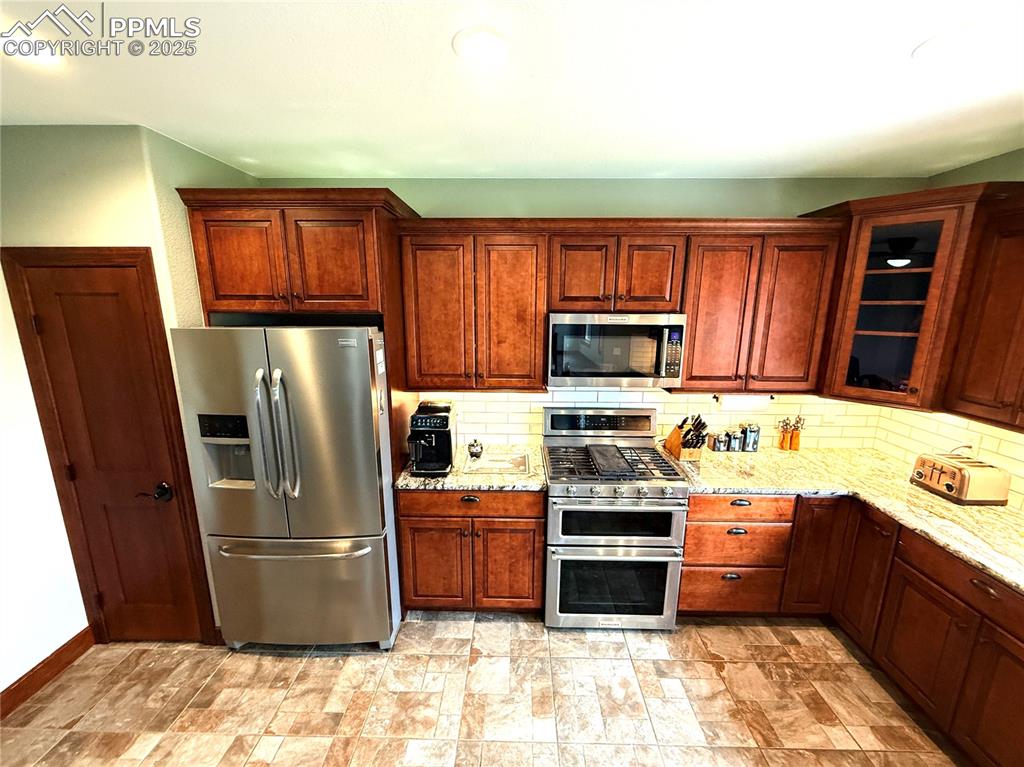 Image 5 of 50: Kitchen with appliances with stainless steel finishes, glass insert cabinet