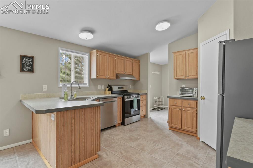Image 11 of 37: Kitchen featuring appliances with stainless steel finishes, a peninsula, li