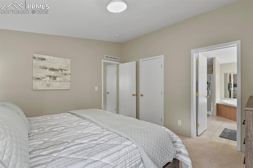 Image 15 of 37: Carpeted bedroom with tile patterned flooring and ensuite bath