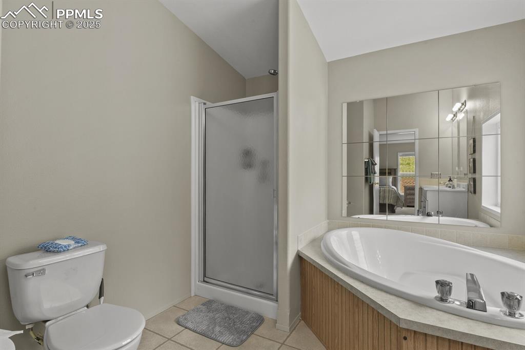 Image 17 of 37: Full bathroom featuring light tile patterned floors, a stall shower, a bath