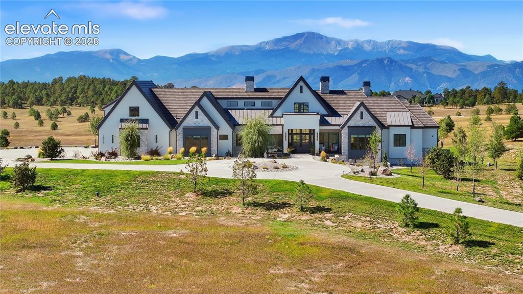 Caption: Modern farmhouse estate featuring a striking dual-gable architectural design with light-colored exte