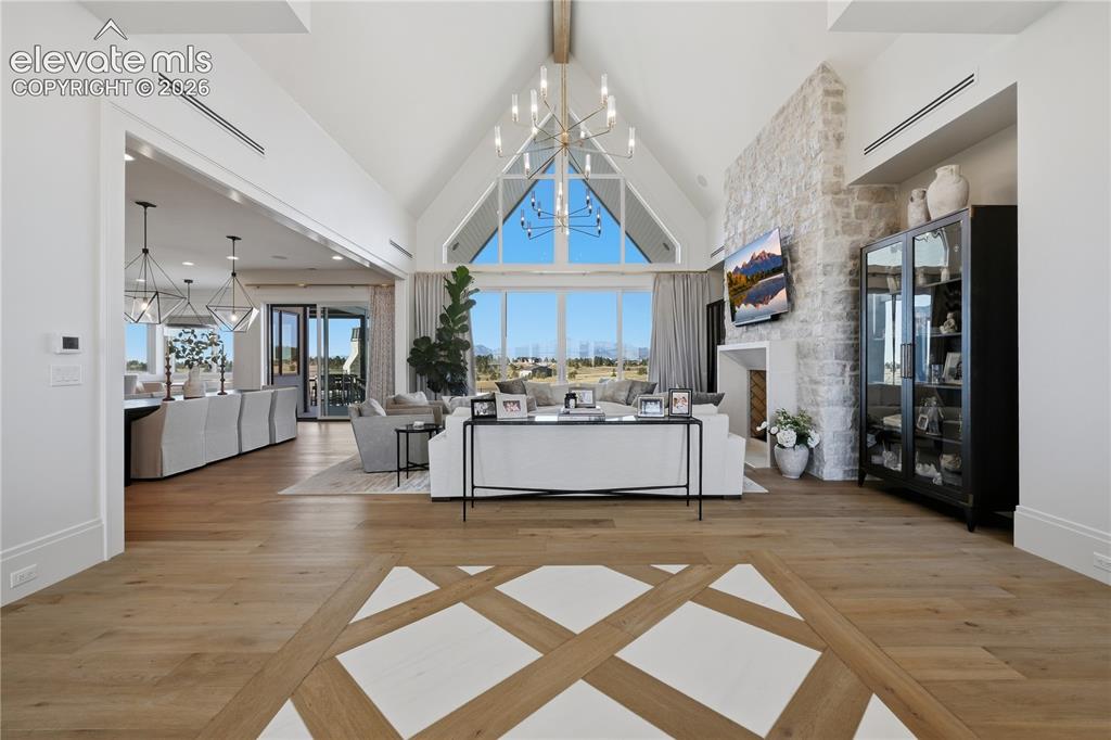 Image 11 of 50: Vaulted ceiling with exposed structural beam, floor-to-ceiling stone firepl