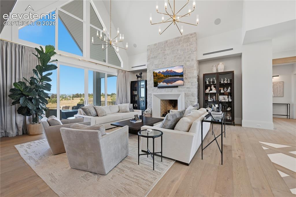 Image 13 of 50: Vaulted ceilings with expansive floor-to-ceiling windows, stone-clad firepl