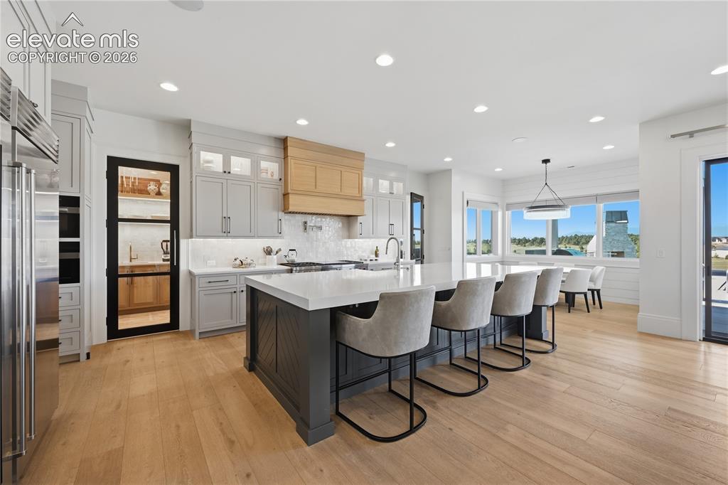 Image 16 of 50: Gourmet kitchen featuring a large center island, custom cabinetry, wood-fin