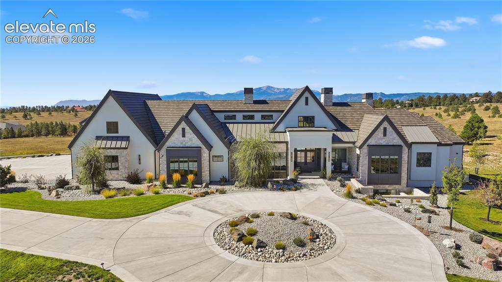 Image 2 of 50: Multi-gabled exterior featuring light-toned masonry, shingle and metal roof