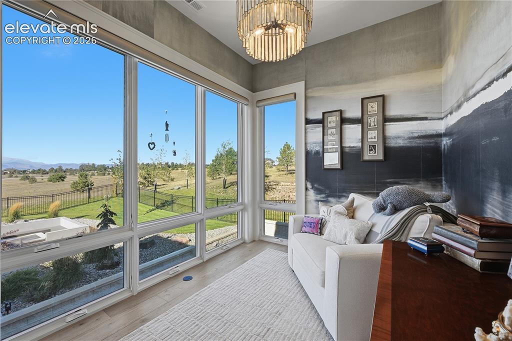 Image 25 of 50: Floor-to-ceiling windows, wood-finish flooring, and tiered crystal chandeli