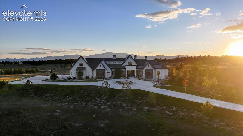 Image 40 of 50: Multi-gabled estate featuring a light-toned exterior, steep rooflines, a ci
