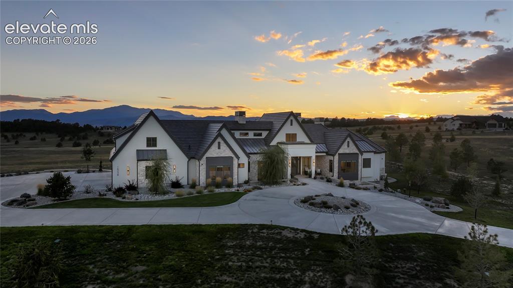 Image 43 of 50: Multi-gabled exterior featuring white masonry and stone accents, concrete c
