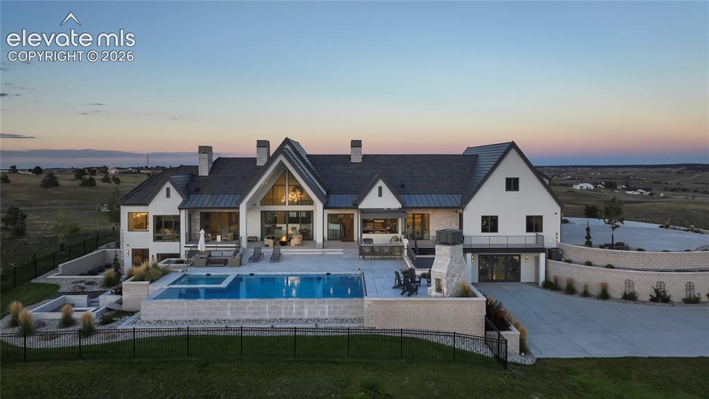 Image 45 of 50: Stucco and stone exterior featuring a multi-gabled roofline, an infinity-ed