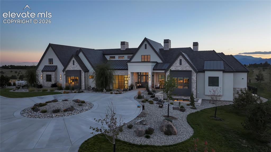 Image 47 of 50: Custom estate featuring a stone and stucco facade, multi-gabled roofline, e