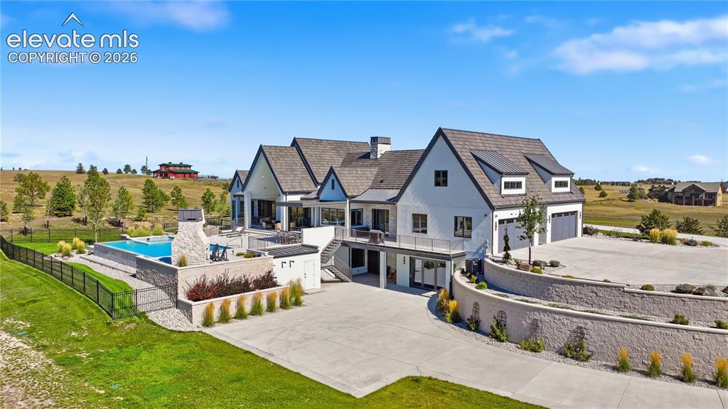 Image 5 of 50: Multi-level exterior featuring white masonry, a dark pitched roof, an expan