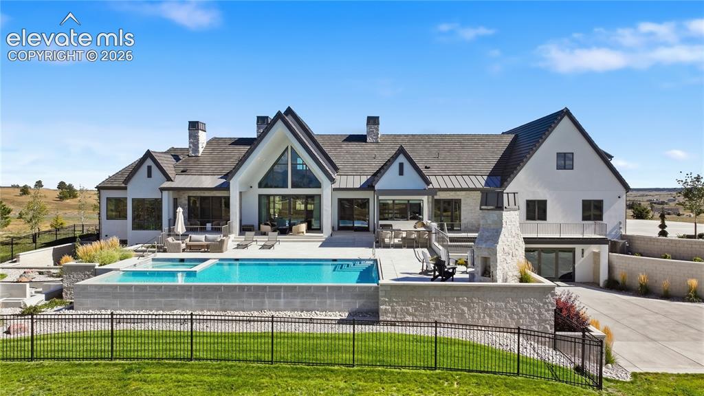 Image 6 of 50: Multi-gabled exterior featuring white masonry and stone siding, expansive r
