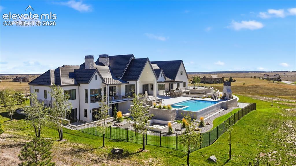 Image 7 of 50: Multi-gabled estate featuring white stucco siding, a tiled roof, an elevate