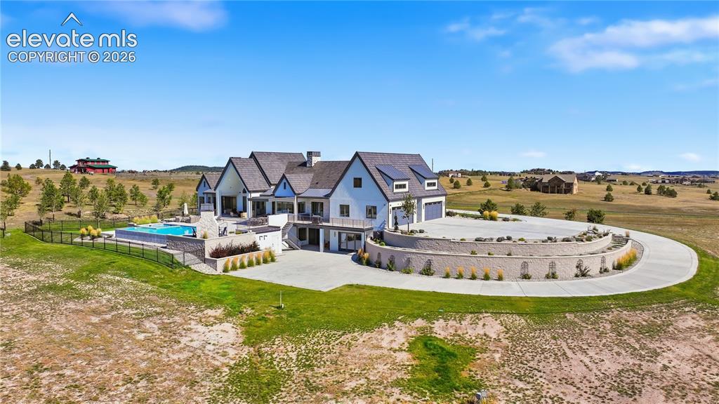 Image 8 of 50: Multi-level residence featuring a dark shingle roof, integrated solar panel