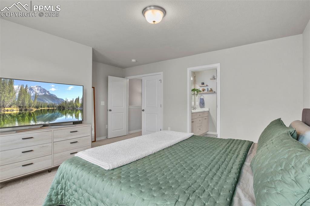 Image 23 of 34: Bedroom featuring ensuite bathroom, baseboards, and light carpet