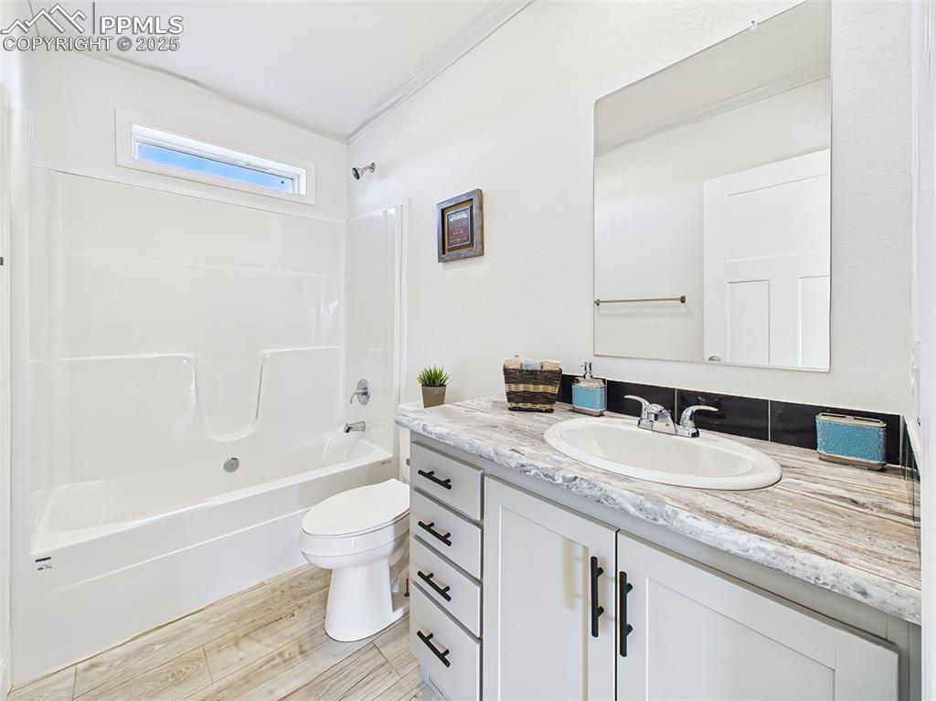 Image 38 of 50: Bright full bath with single-sink vanity, wood-look tile floors, and modern