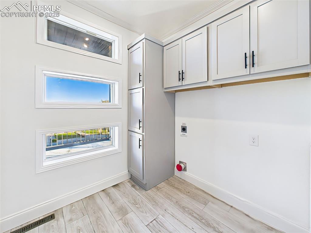 Image 39 of 50: Dedicated laundry space with custom cabinetry, and unique window detail add