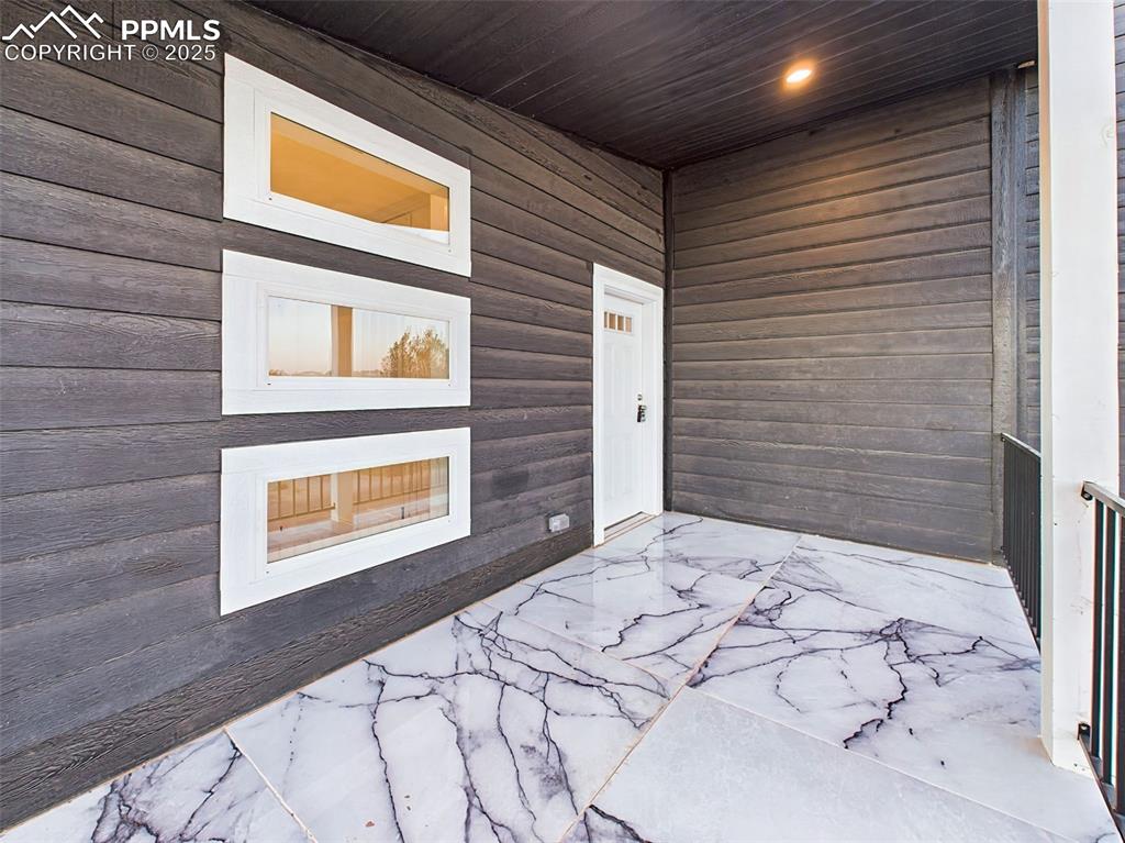 Image 45 of 50: Distinctive front entry with modern dark siding, recessed lighting, and sle