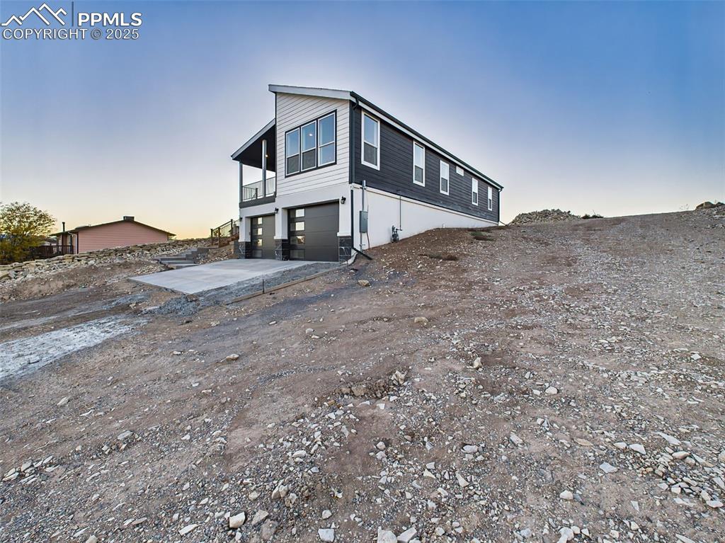 Image 46 of 50: Wide perspective of home showing newly poured driveway, 2-car garage, and e